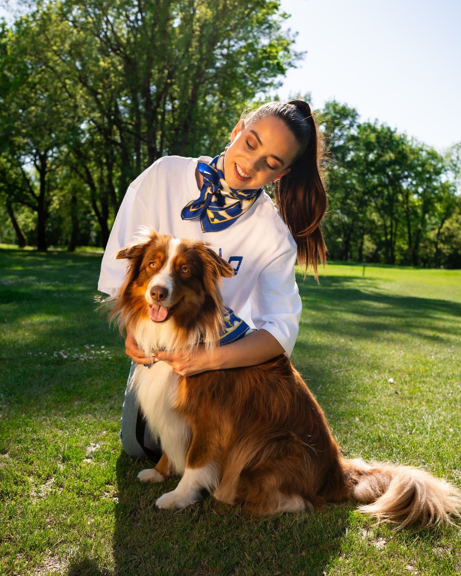 Camille Marchandeau avec le t-shirt et le foulard en soie gentes en train de carresser son chien.