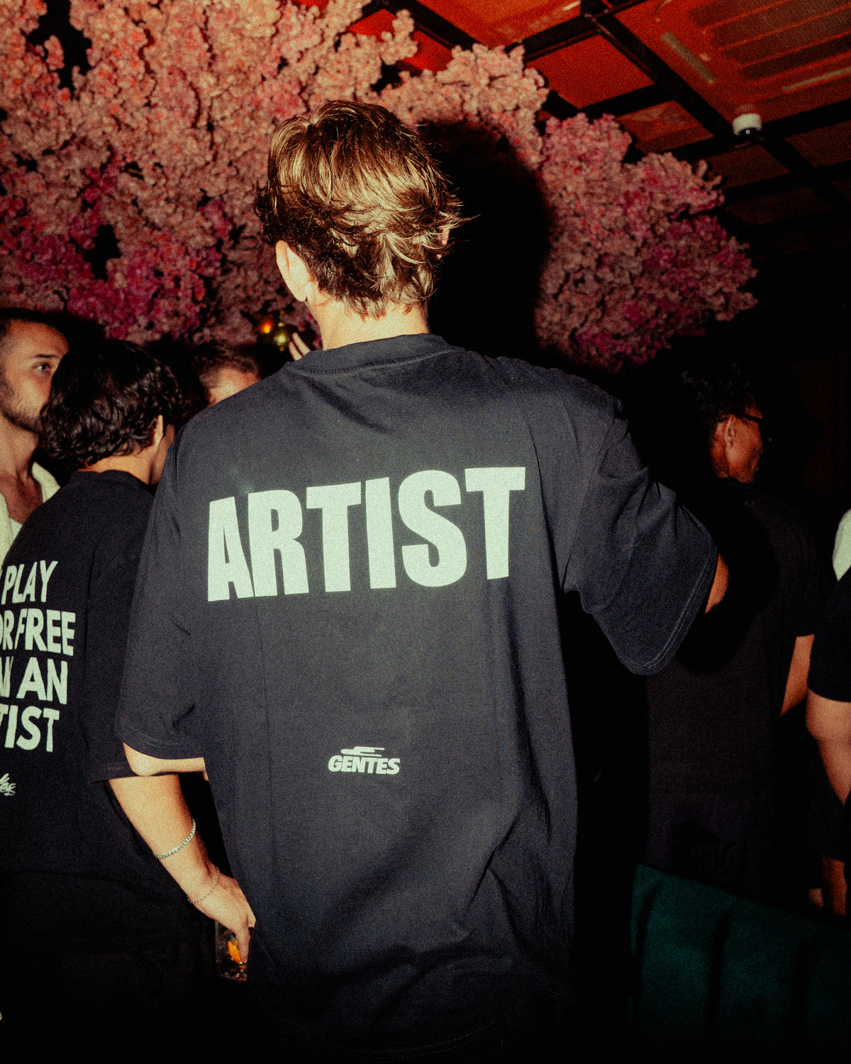 Mannequin qui porte le t-shirt noir avec inscription "ARTIST3 au dos, dans une soirée  Bali.