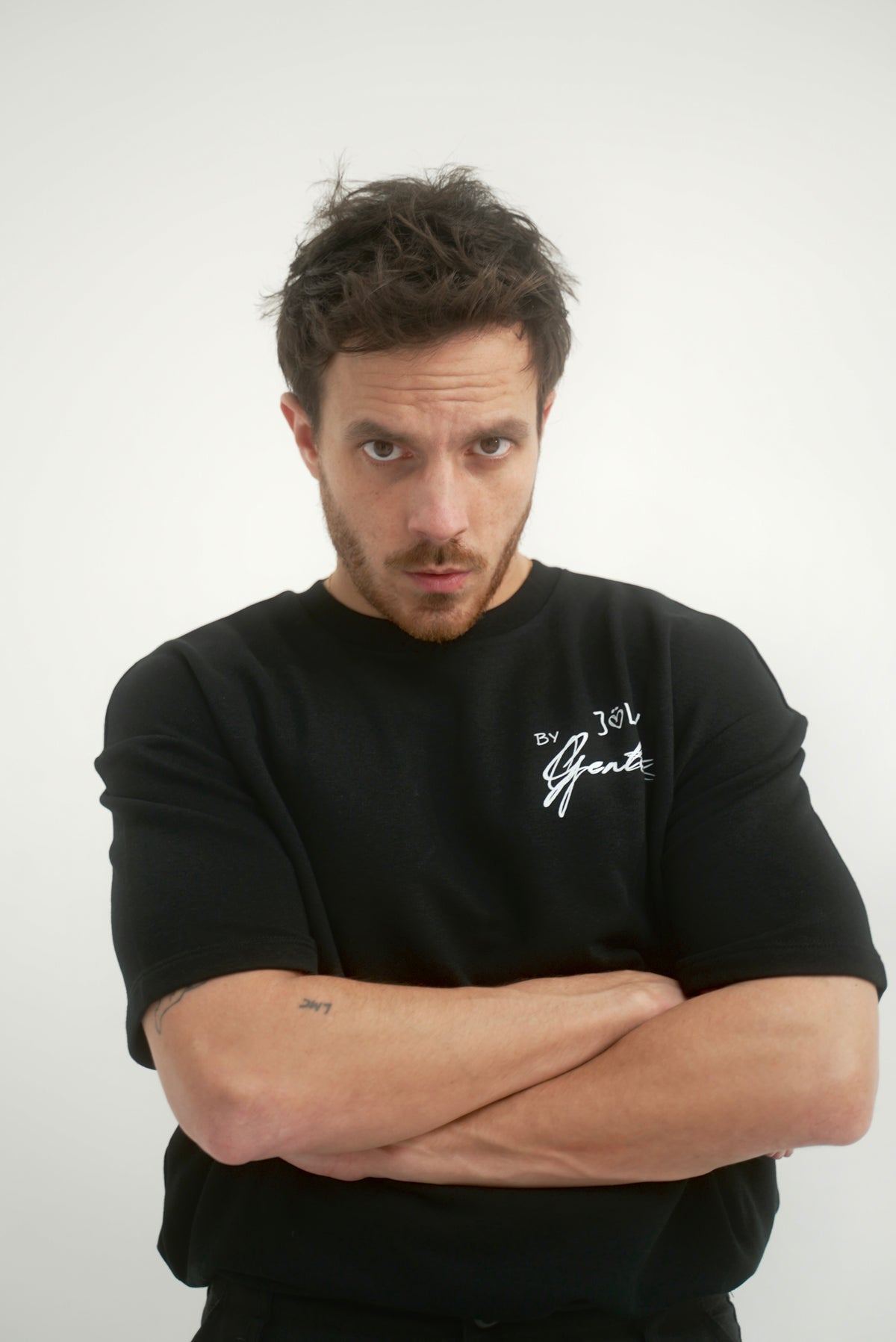 Mannequin masculin avec un regard fort et les bras croisé qui porte le t-shirt avec le coeur